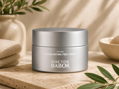 DOCTOR BABOR 5% AHA Exfoliating Peel Pads in elegantem silbernen Tiegel vor modernem Spa-Hintergrund mit warmen Beige- und Naturtönen, Naturstein und stilvollen Wellness-Elementen. Hochwertige Beauty-Produktinszenierung mit cleanem Luxus-Look und entspannender Spa-Atmosphäre