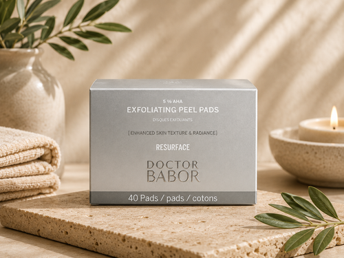 DOCTOR BABOR 5% AHA Exfoliating Peel Pads in elegantem silbernen Tiegel vor modernem Spa-Hintergrund mit warmen Beige- und Naturtönen, Naturstein und stilvollen Wellness-Elementen. Hochwertige Beauty-Produktinszenierung mit cleanem Luxus-Look und entspannender Spa-Atmosphäre